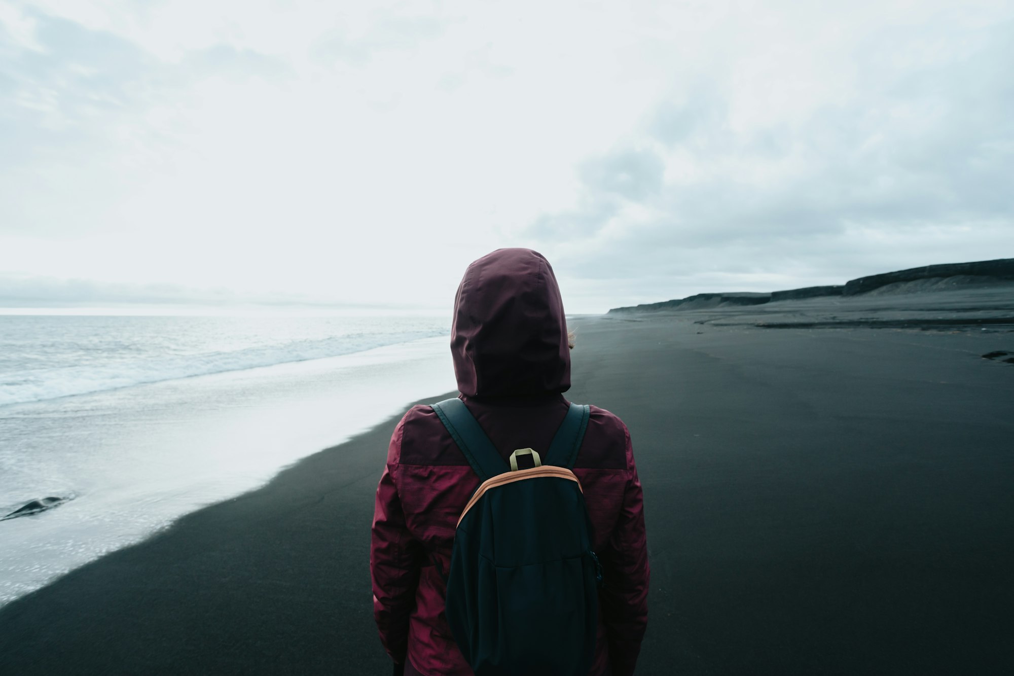 Female solo traveler in a black sand beach in Iceland diamond beach, during a sunny day. Exploring a